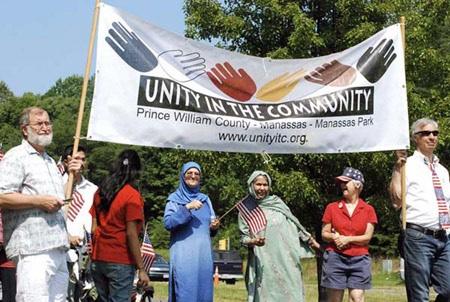 A group of 6 people holding up a "Unity In The Community" banner